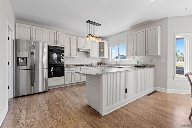 kitchen featuring glass insert cabinets, a peninsula, stainless steel appliances, light wood-type flooring, and under cabinet range hood