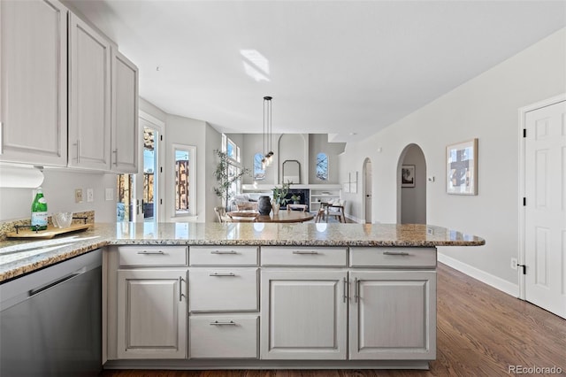 kitchen with dark wood-style floors, arched walkways, light stone counters, dishwasher, and a peninsula