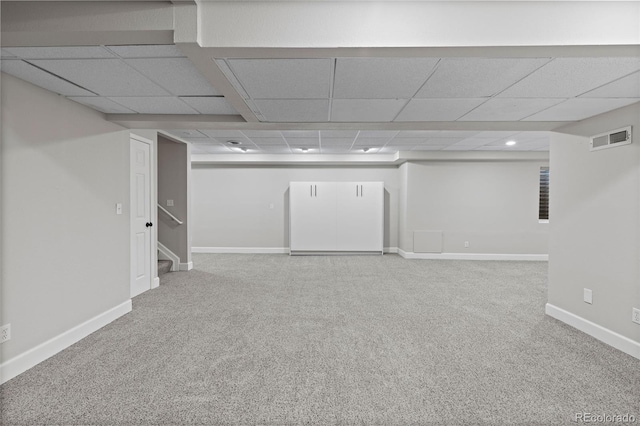 finished basement with carpet, visible vents, a drop ceiling, and baseboards