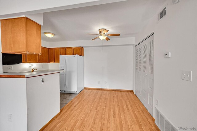 420 Zang St Unit 108, Lakewood, CO 80228 - kitchen featuring light wood-style flooring, visible vents, brown cabinets, white fridge with ice dispenser, and a ceiling fan