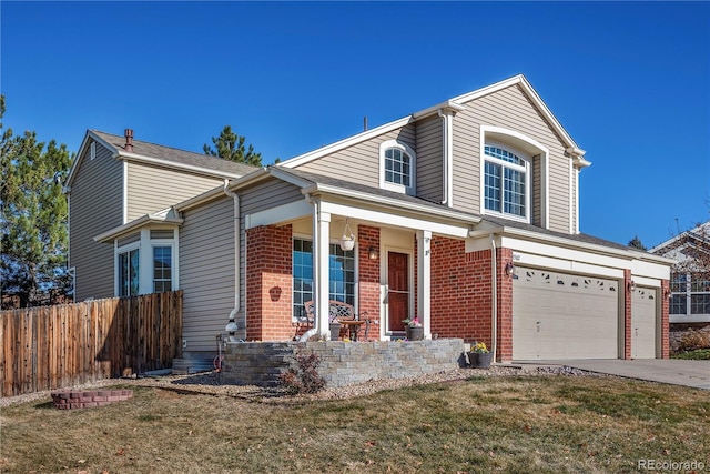 front of property featuring covered porch, a garage, and a front yard