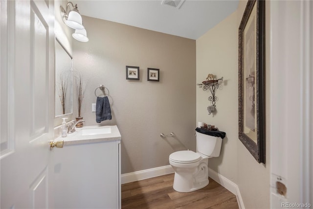 bathroom with hardwood / wood-style floors, vanity, and toilet