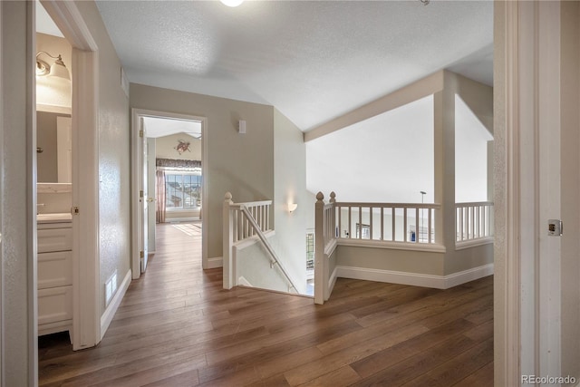 hallway with a textured ceiling and dark hardwood / wood-style flooring