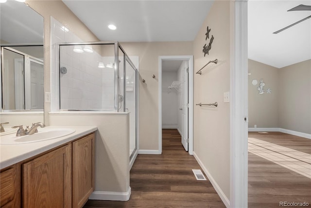 bathroom featuring hardwood / wood-style floors, vanity, a shower with shower door, and vaulted ceiling