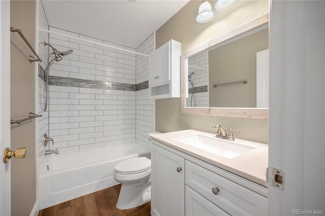 full bathroom featuring vanity, hardwood / wood-style flooring, toilet, and tiled shower / bath combo