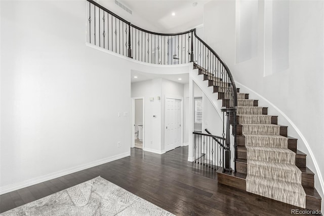 stairs with hardwood / wood-style flooring and a towering ceiling