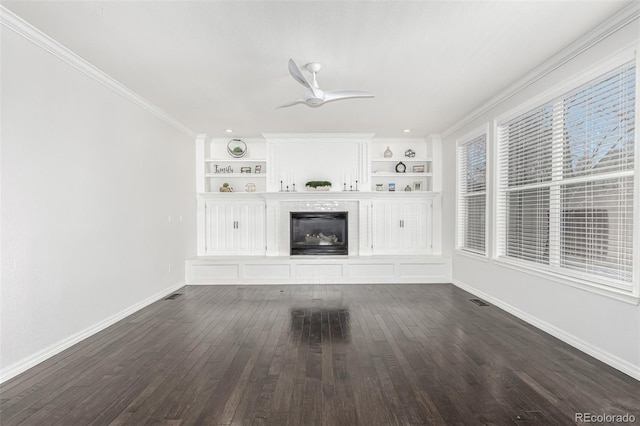 unfurnished living room featuring built in shelves, ceiling fan, crown molding, and dark hardwood / wood-style flooring