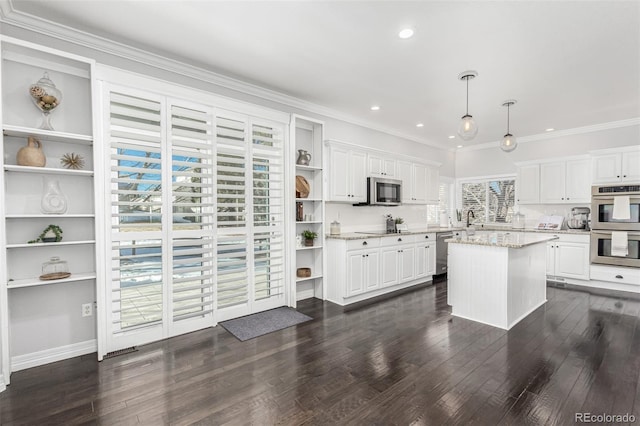 kitchen featuring pendant lighting, appliances with stainless steel finishes, light stone counters, white cabinets, and a kitchen island