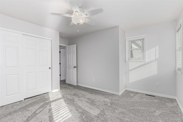 unfurnished bedroom with ceiling fan, light colored carpet, and a closet