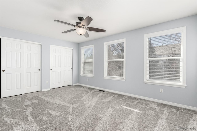 unfurnished bedroom featuring multiple windows, multiple closets, and ceiling fan