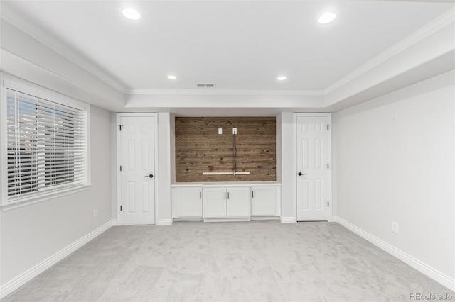 unfurnished bedroom with light carpet, a tray ceiling, and ornamental molding