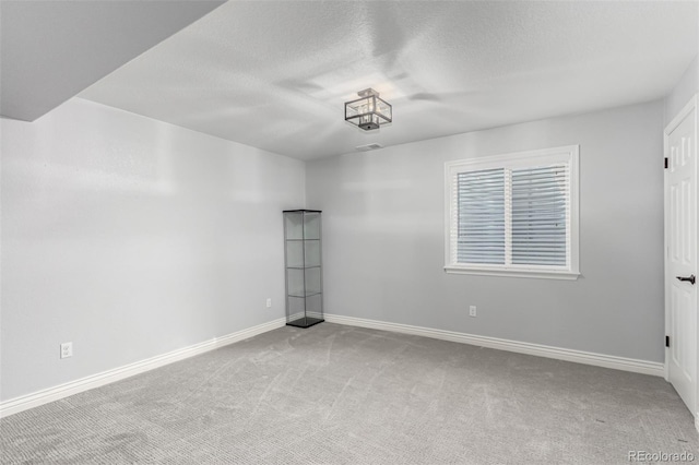 carpeted empty room featuring a textured ceiling