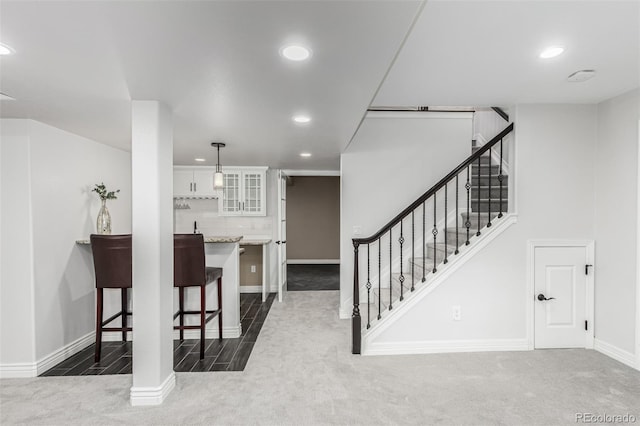 kitchen featuring hanging light fixtures, white cabinetry, a kitchen bar, and kitchen peninsula