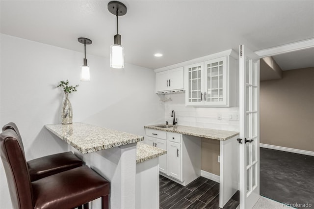 kitchen with a kitchen bar, sink, white cabinetry, kitchen peninsula, and pendant lighting