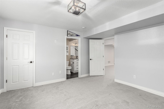 unfurnished bedroom featuring ensuite bath and carpet floors