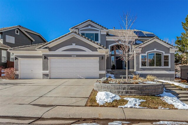 view of front of house featuring a tiled roof, stucco siding, an attached garage, and concrete driveway