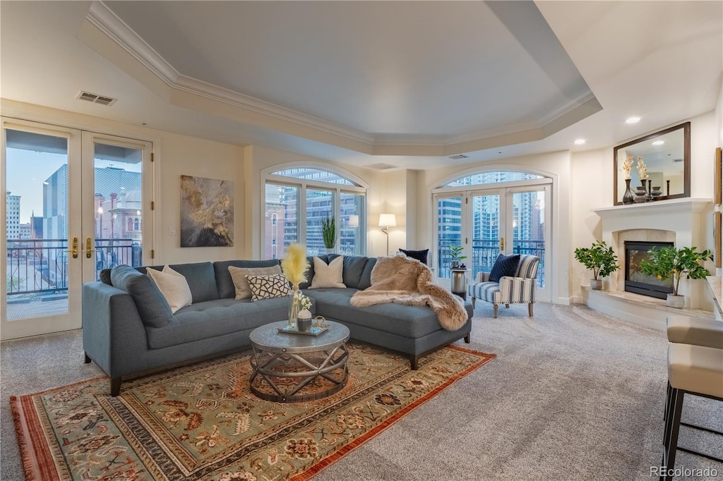 carpeted living room with a tray ceiling, french doors, and crown molding