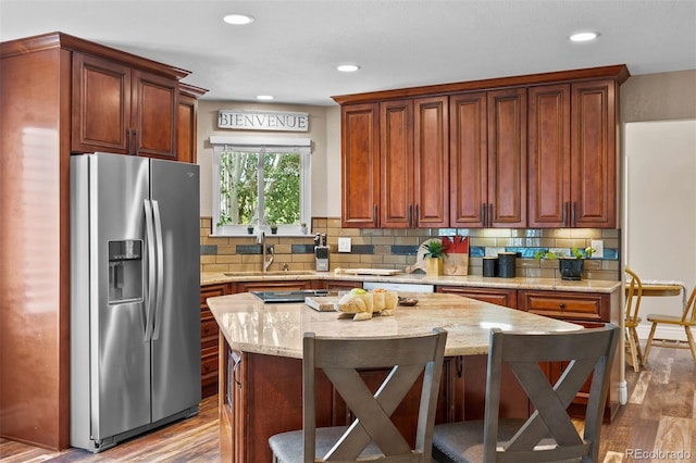 603 E 2nd Ave, Castle Rock, CO 80108 - kitchen featuring stainless steel fridge with ice dispenser, light wood-type flooring, tasteful backsplash, a breakfast bar area, and recessed lighting