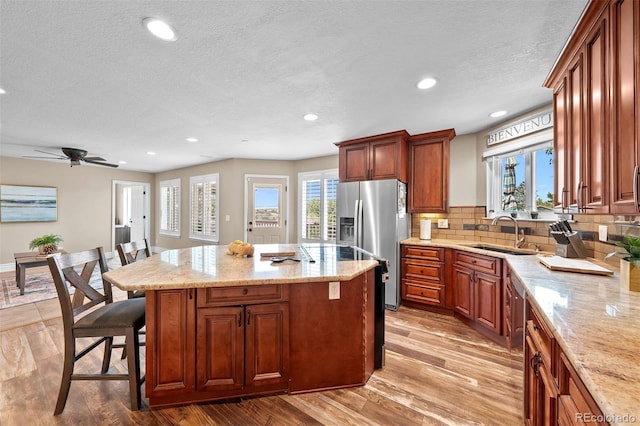 603 E 2nd Ave, Castle Rock, CO 80108 - kitchen featuring stainless steel fridge with ice dispenser, a center island, light wood-style floors, a kitchen bar, and a textured ceiling