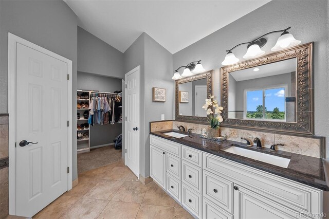 603 E 2nd Ave, Castle Rock, CO 80108 - full bathroom with double vanity, vaulted ceiling, a walk in closet, and tile patterned floors
