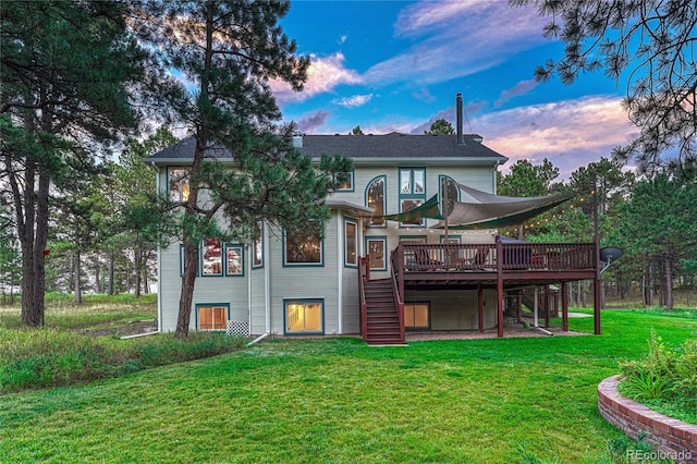 back house at dusk with a deck and a lawn