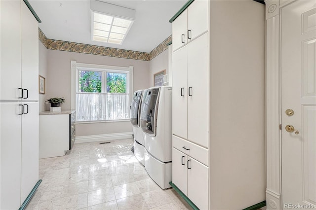 laundry room with light tile patterned floors, cabinets, and washing machine and clothes dryer