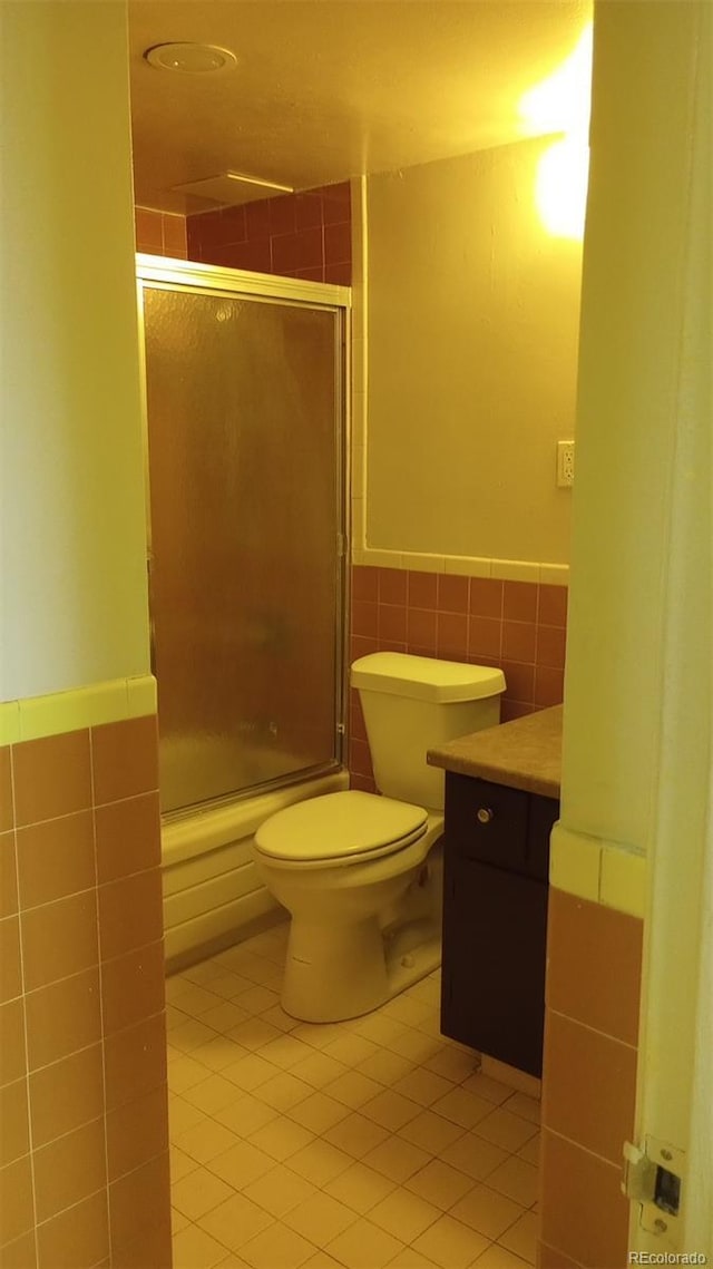 full bathroom with vanity, tile patterned flooring, toilet, enclosed tub / shower combo, and tile walls