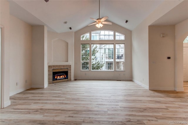 unfurnished living room featuring baseboards, high vaulted ceiling, a fireplace, ceiling fan, and light wood-type flooring