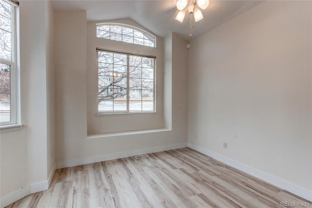 empty room with light wood-type flooring, visible vents, a ceiling fan, baseboards, and vaulted ceiling