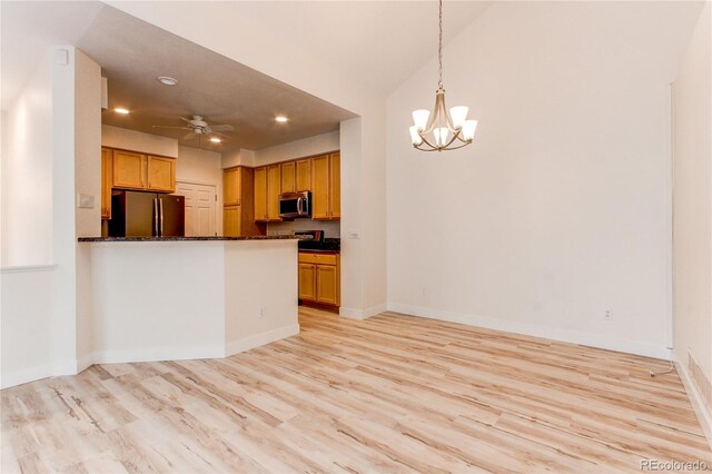 kitchen featuring stainless steel microwave, baseboards, light wood-style flooring, ceiling fan with notable chandelier, and freestanding refrigerator