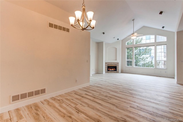 unfurnished living room with light wood-type flooring, visible vents, ceiling fan with notable chandelier, and a tile fireplace