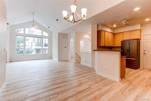 kitchen with light wood-type flooring, ceiling fan with notable chandelier, arched walkways, and freestanding refrigerator