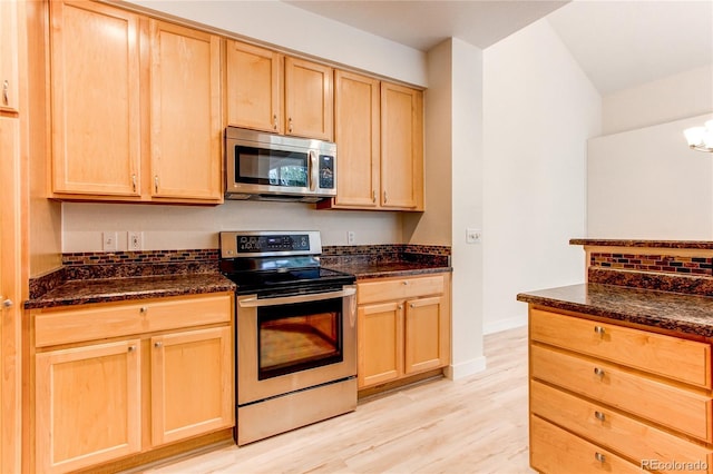 kitchen with dark stone counters, appliances with stainless steel finishes, and light brown cabinets