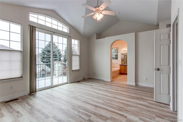 spare room featuring visible vents, light wood finished floors, lofted ceiling, arched walkways, and ceiling fan