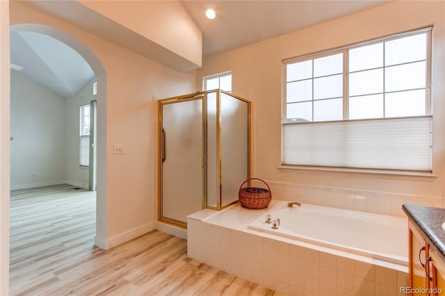 full bath with lofted ceiling, a garden tub, wood finished floors, and a shower stall