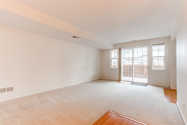 spare room featuring light colored carpet and visible vents