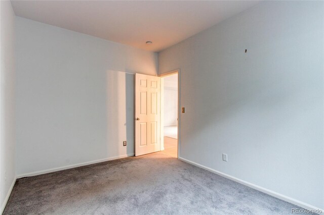 carpeted spare room featuring baseboards