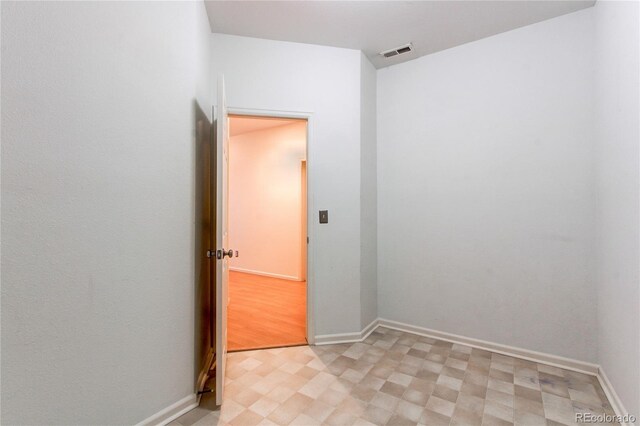 spare room featuring visible vents, baseboards, and light floors