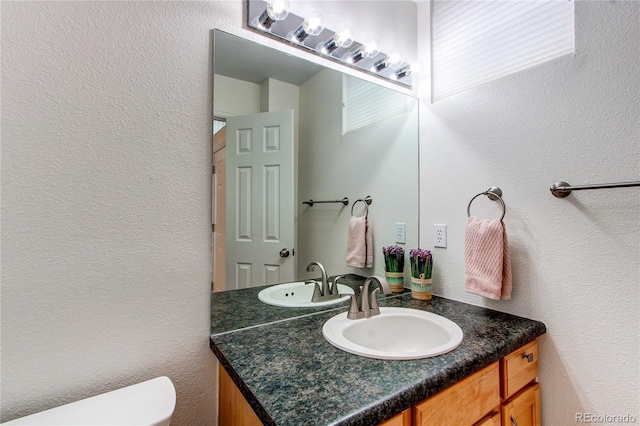 bathroom featuring vanity, toilet, and a textured wall