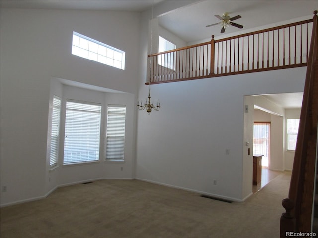 interior space with a towering ceiling, baseboards, visible vents, and ceiling fan with notable chandelier