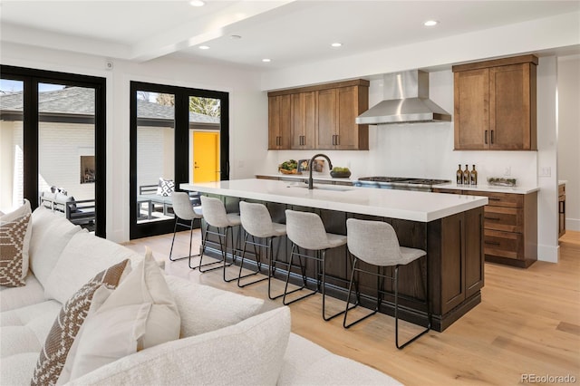 1195 S Milwaukee St, Denver, CO 80210 - kitchen featuring wall chimney range hood, a sink, light wood-style floors, light countertops, and recessed lighting