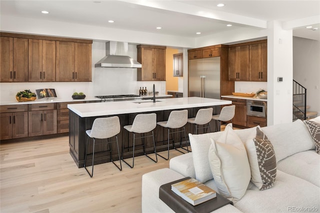 1195 S Milwaukee St, Denver, CO 80210 - kitchen with wall chimney exhaust hood, a sink, recessed lighting, light wood finished floors, and light countertops