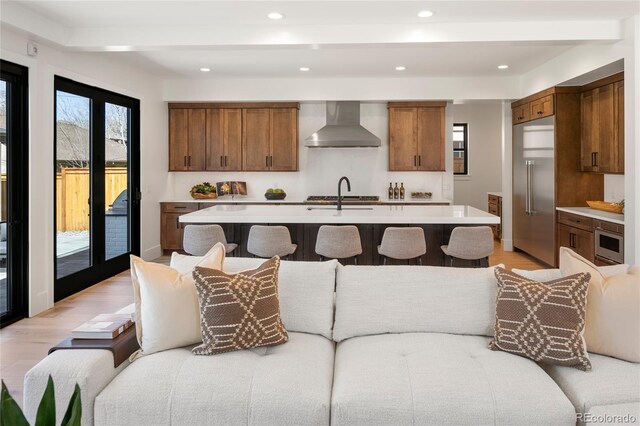 1195 S Milwaukee St, Denver, CO 80210 - kitchen with wall chimney exhaust hood, light countertops, brown cabinets, stainless steel built in refrigerator, and a sink