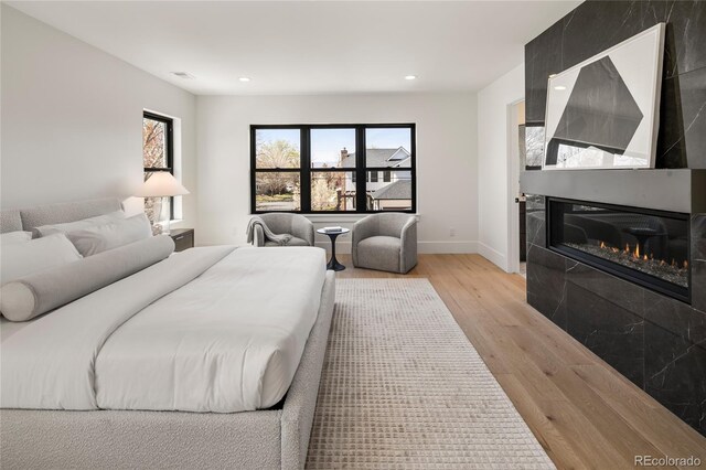 1195 S Milwaukee St, Denver, CO 80210 - bedroom featuring light wood-type flooring, recessed lighting, a glass covered fireplace, and baseboards