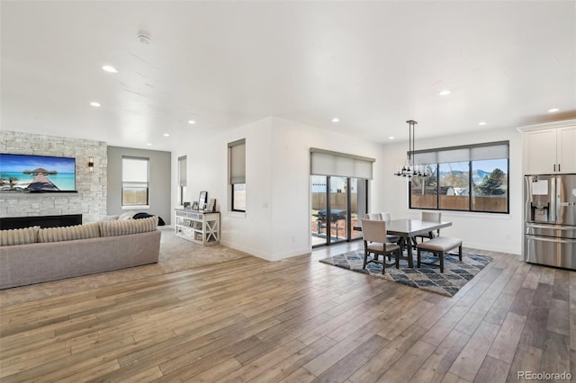 dining area featuring hardwood / wood-style floors, a notable chandelier, and a stone fireplace