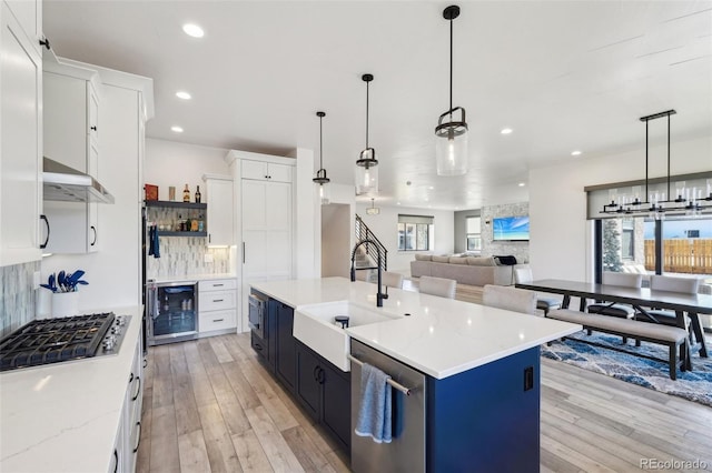 kitchen featuring hanging light fixtures, decorative backsplash, white cabinetry, and a center island with sink