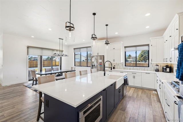 kitchen featuring stainless steel appliances, pendant lighting, white cabinetry, and a spacious island