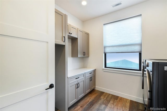 kitchen featuring gray cabinets, dark hardwood / wood-style floors, and washer / dryer