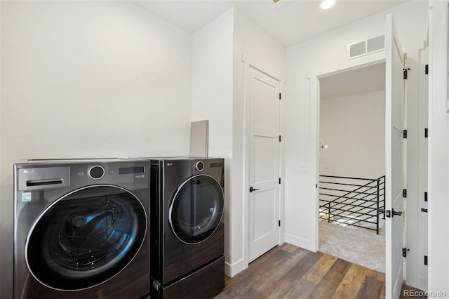 clothes washing area featuring dark hardwood / wood-style flooring and washer and clothes dryer