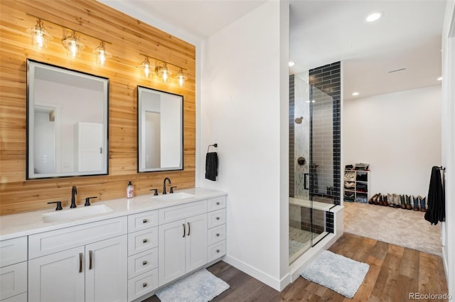 bathroom featuring vanity, walk in shower, hardwood / wood-style flooring, and wooden walls